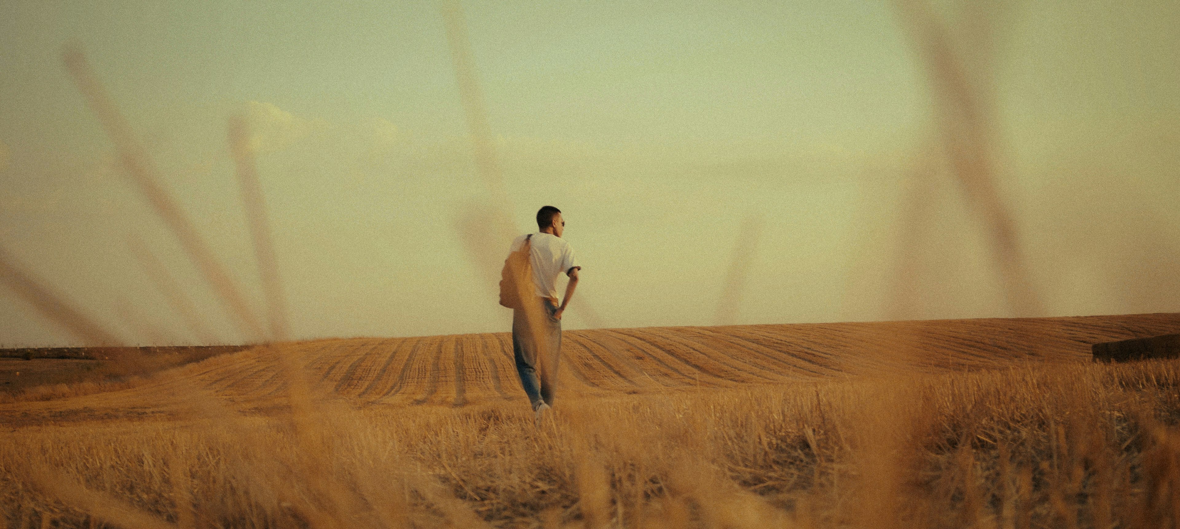 man in white shirt and brown pants standing on brown field during daytime